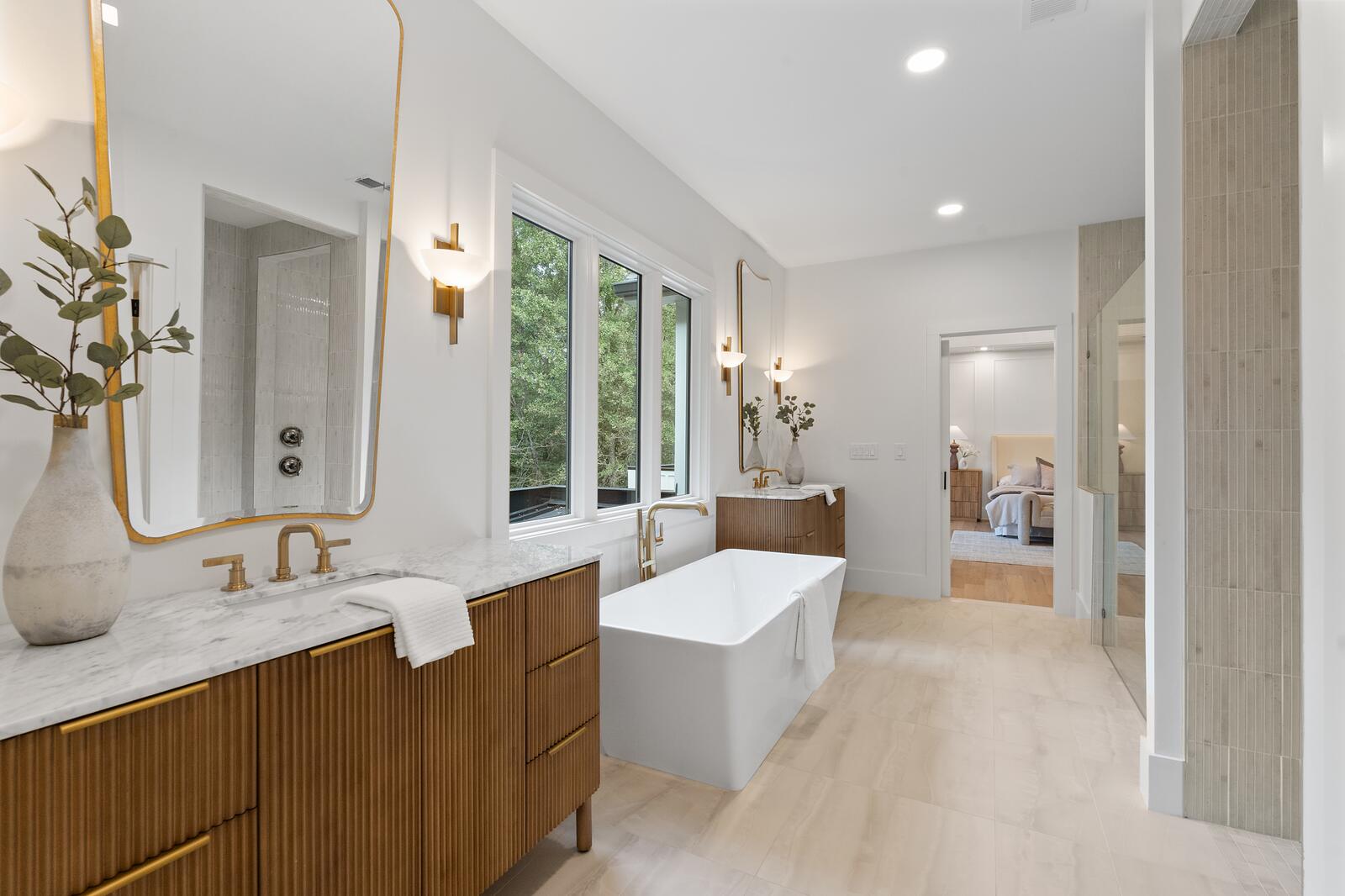A primary bathroom with a freestanding tub, wood vanity, and brass fittings