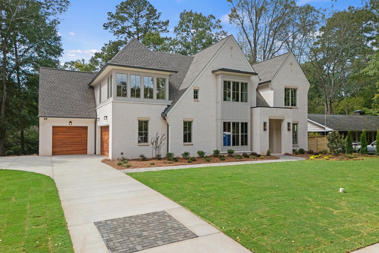 A completed new home in painted brick with gabled rooflines and a finished lawn